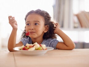 Niña vegetariana comiendo un plato de frutas