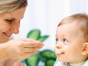 Bebé pequeño comiendo papilla de fruta.