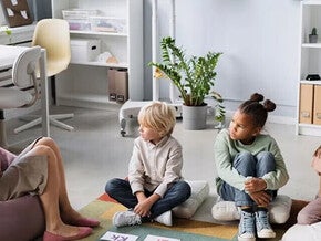 Patólogo del habla y lenguaje, SLP terapeuta del habla y lenguaje, fonoaudiólogo mostrando abecedario a niños pequeños sentados sobre cojines.