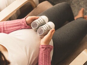 Conoce qué es el bebé arcoíris.  Mamá embarazada de un bebé arcoíris cogiendo unos zapatitos.