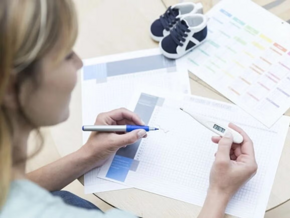 Mujer sonriendo y viendo prueba de embarazo.