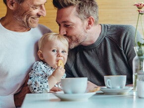 Niña comiendo galletas para bebés con su papá y abuelo.
