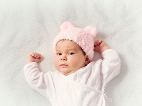 Conoce el desarrollo de un bebé de dos meses.  Bebé de dos meses acostada alzando los brazos.