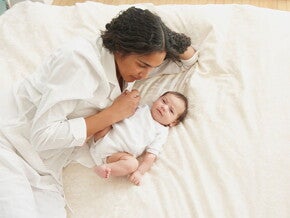 Mamá acostada con su bebé de tres meses.