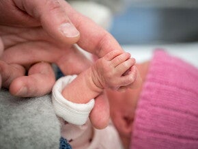 Mamá cogiendo la mano de su bebé de un mes.