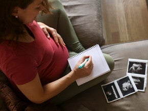 Tener un embarazo múltiple es muy común.  Mamá con un cuaderno mirando la ecografía de su embarazo múltiple.