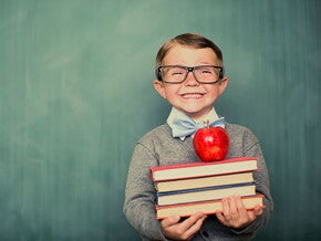 Niño sonriendo con libros en la mano.