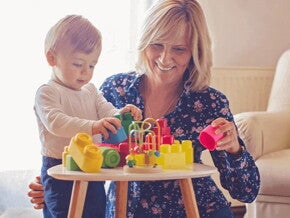 Mamá y bebé jugando con bloques para estimular el desarrollo psicomotor.