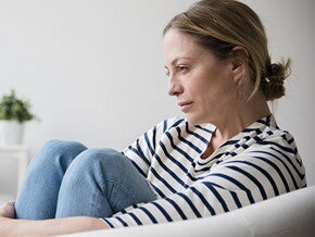 Mujer con depresión posparto sentada en el sofá, triste. 
