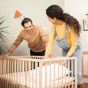 Un hombre y una mujer preparan la cuna del bebé