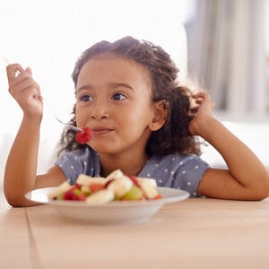 Niña vegetariana comiendo un plato de frutas