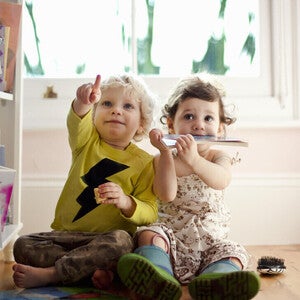 Niño y niña de dos años sentados en el piso, señalando. Concepto de comunicación y desarrollo de lenguaje.