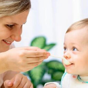 Mamá dando de comer papilla a su bebé como parte de la alimentación complementaria.