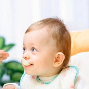 Bebé pequeño comiendo papilla de fruta.