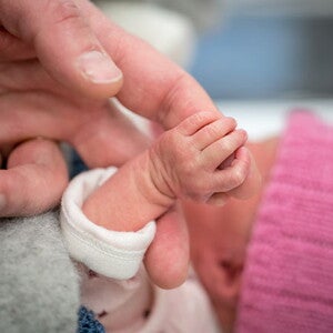 Mamá cogiendo la mano de su bebé de un mes.