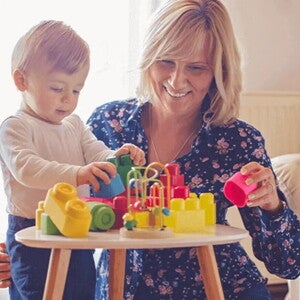 Mamá y bebé jugando con bloques para estimular el desarrollo psicomotor.