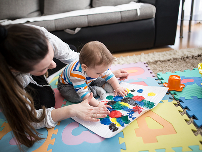 Actividades y juegos divertidos para estimular el desarrollo cognitivo Una mujer y un bebé jugando en una alfombra colorida.