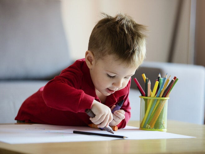 Niño pequeño coloreando una hoja blanca
