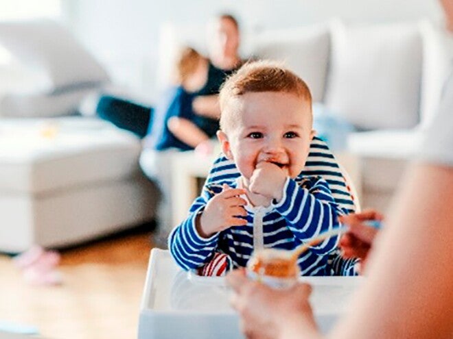 Guía para darle alimentos sólidos a tu bebé Bebé en su silla comiendo alimentos sólidos