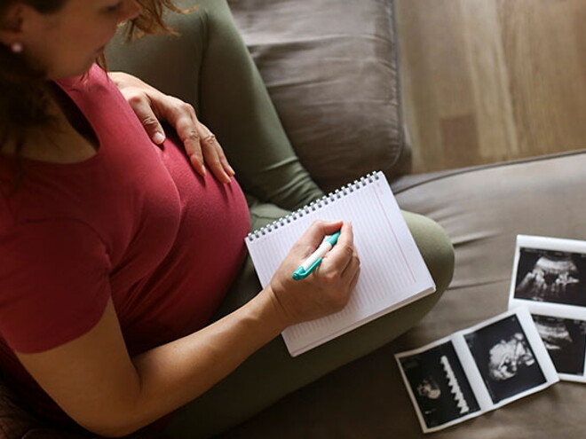 Tener un embarazo múltiple es muy común. Mamá con un cuaderno mirando la ecografía de su embarazo múltiple.