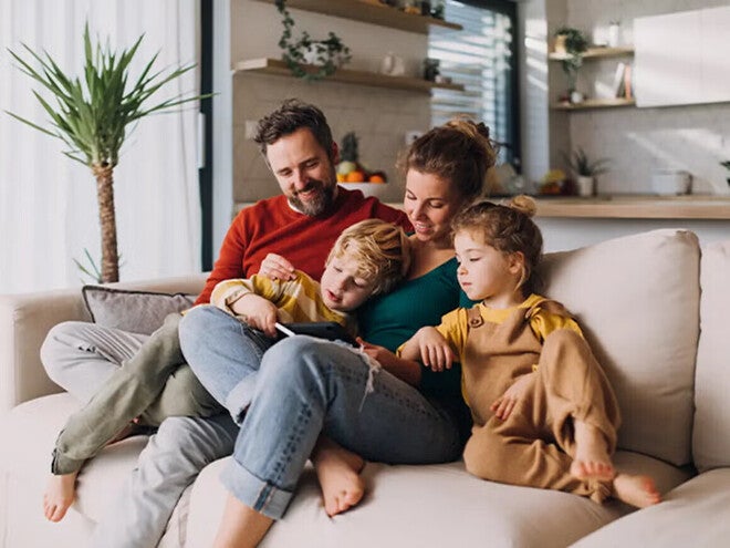 Familia sentada en un sofá en una sala de estar, leyendo un libro