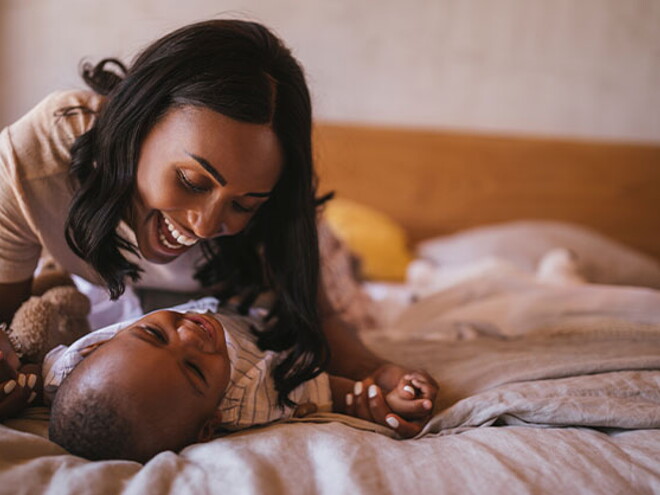 La mamá y el bebé haciendo ejercicios en la cama La mamá y el bebé haciendo ejercicios en la cama