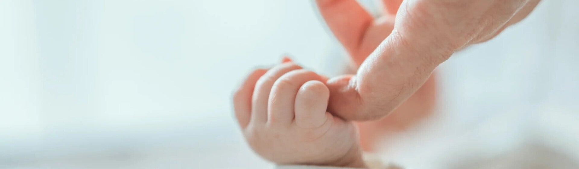 Bebé sujetando el dedo de su mamá