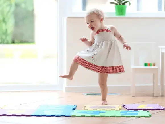 Qué son las actividades sensoriales niña bailando sobre tapetes de goma para jugar
