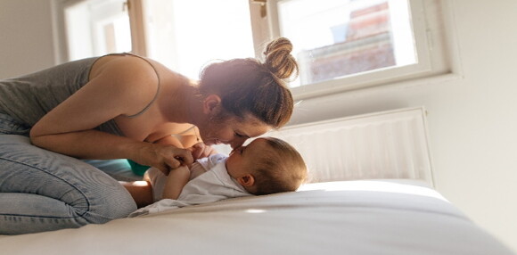 Bebé acostado y mamá jugando con él