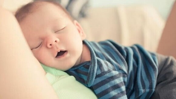 Bebé durmiendo encima de la madre, boca abierta y respirando por la boca.