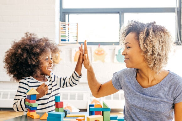 Niña pequeña y mamá jugando juntas, chocando los cinco.