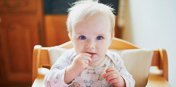 Conoce cuáles son los beneficios de darle galletas a tu hijo. Niña comiendo galletas sola.