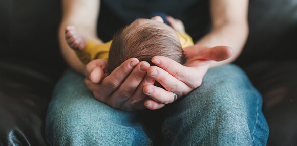 Una de las causas de los granitos en la cara de los bebés son las hormonas maternas Papá alzando su bebé en sus piernas