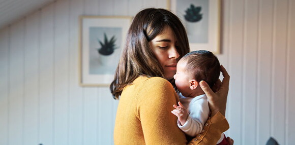 El vínculo con los padres hace parte del desarrollo emocional del bebé de un mes. Mamá cargando a su bebé de un mes.