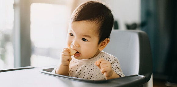 Conoce cuáles son los beneficios de darle galletas a tu hijo. Niña comiendo galletas para bebés.
