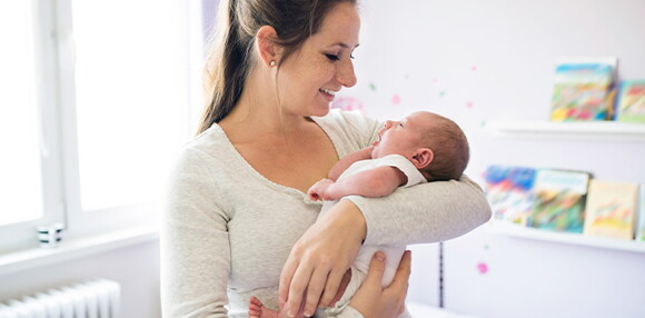 Uno de los cuidados que debes tener para los granitos en la cara del bebé es la limpieza Mamá alzando a su bebé y mirando su cara