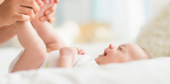 Un bebé de dos meses desarrolla habilidades motoras finas y gruesas. Bebé de dos meses sonriendo con las piernas levantadas.