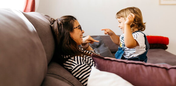 Realiza juegos y explícale por qué es importante los hábitos de higiene. Mamá y niña riendo y hablando de los hábitos de higiene.
