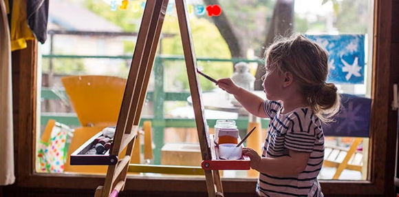 Niña pequeña pintando con pinturas en un lienzo.