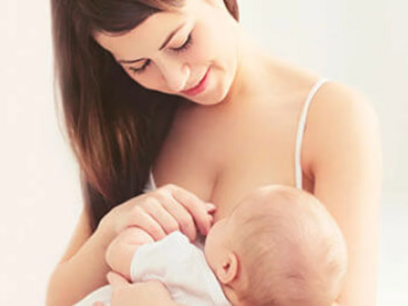 Mamá cargando a un bebé, sonriendo y dándole de amamantar.