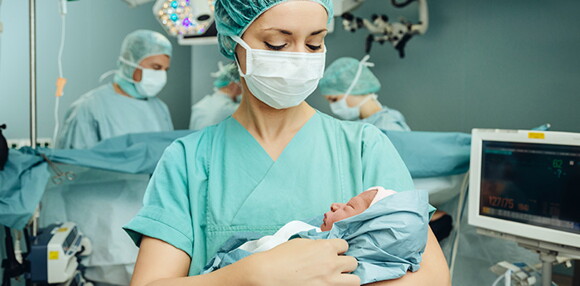 Los médicos son fundamentales para la tranquilidad de la mamá en la inducción del parto. Enfermera alzando al bebé luego del parto inducido.