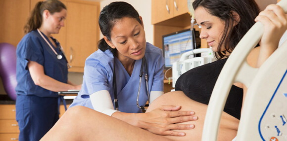 El apoyo del personal médico es fundamental si existe alguna complicación o riesgo en la inducción del parto. Enfermera ayudando a la madre en el proceso del parto inducido.