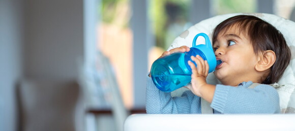 Reconoce las señales para identificar que tu pequeño está bien hidratado. Niño tomando agua de vasito entrenador